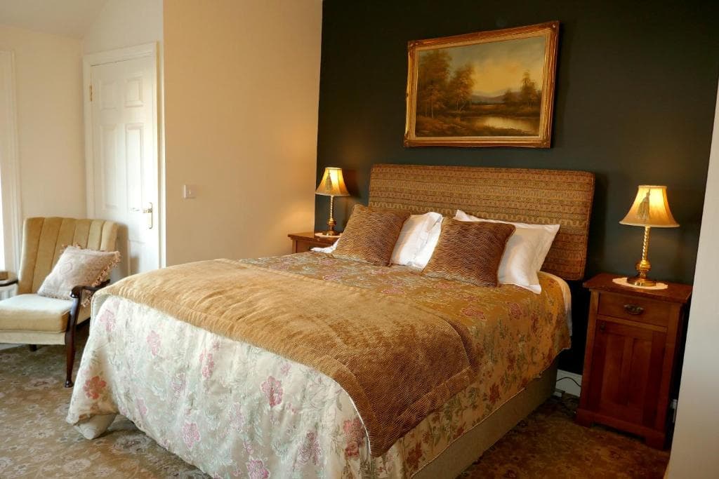 A double room at Crookedstone House, with a wingback chair and bedside lamps